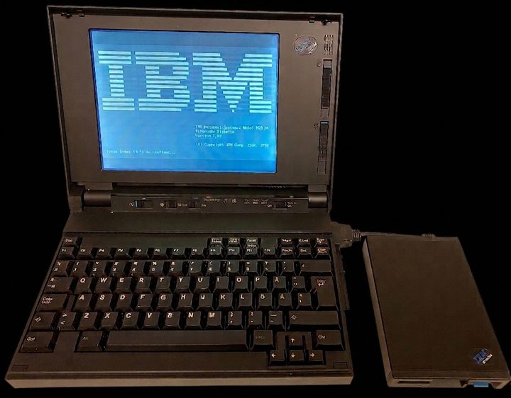 IBM PS/2 Note N33 SX open at its blue IBM start-up screen, with its external diskette drive connected alongside