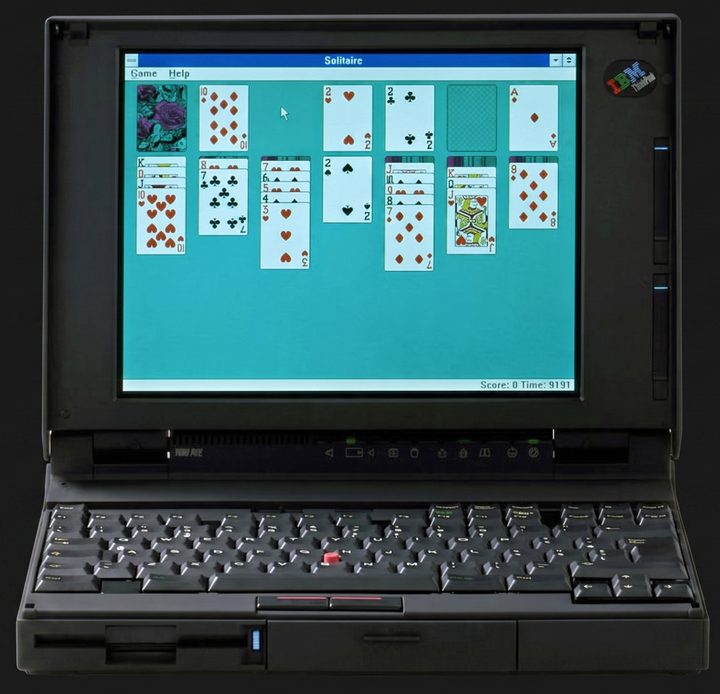 ThinkPad 700C open, with Windows Solitaire on its colour screen, the status indicator strip below the display and the red TrackPoint